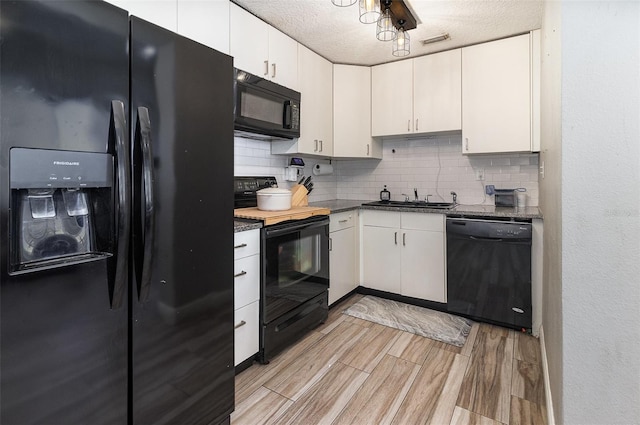 kitchen featuring visible vents, wood finish floors, a sink, black appliances, and backsplash