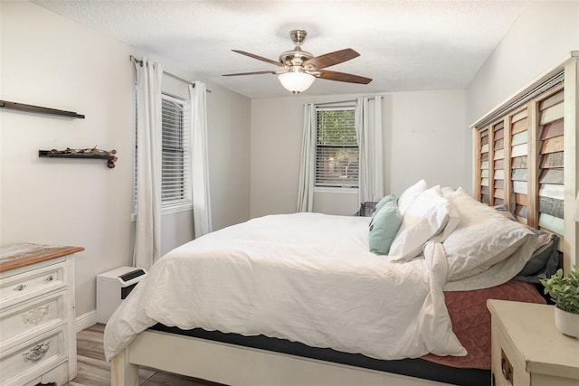 bedroom featuring light wood-style floors, a textured ceiling, and a ceiling fan