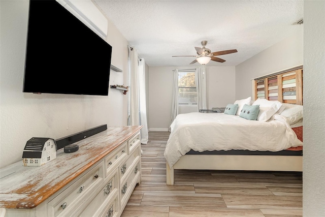 bedroom featuring wood finish floors, a ceiling fan, baseboards, and a textured ceiling