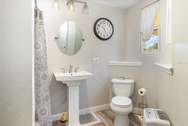 bathroom with a sink, toilet, baseboards, and wood finished floors