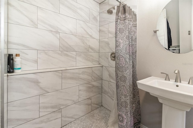 full bath featuring a tile shower and a sink