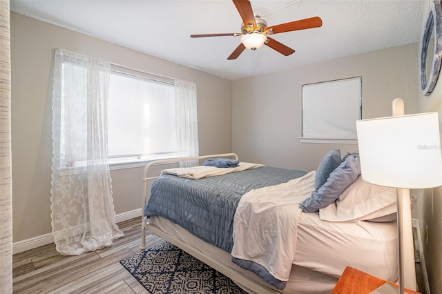 bedroom featuring wood finished floors, a ceiling fan, and baseboards