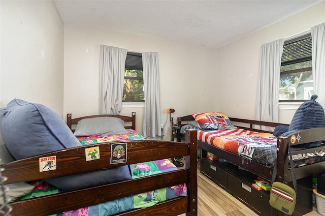 bedroom with multiple windows, wood finished floors, and a textured ceiling