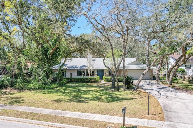 single story home featuring a front lawn, a garage, driveway, and a chimney