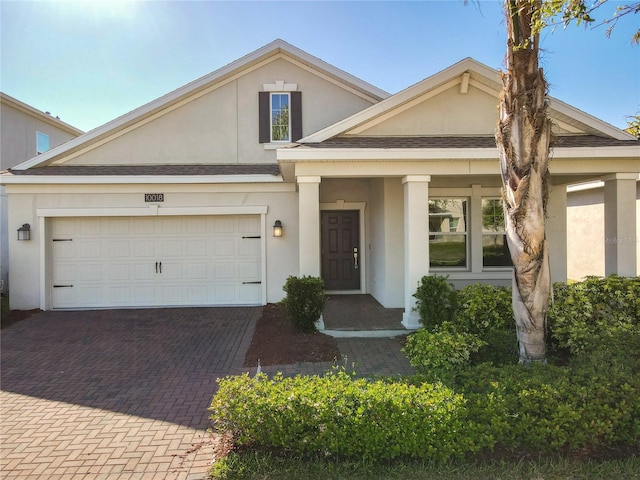 view of front of house with stucco siding, an attached garage, and decorative driveway