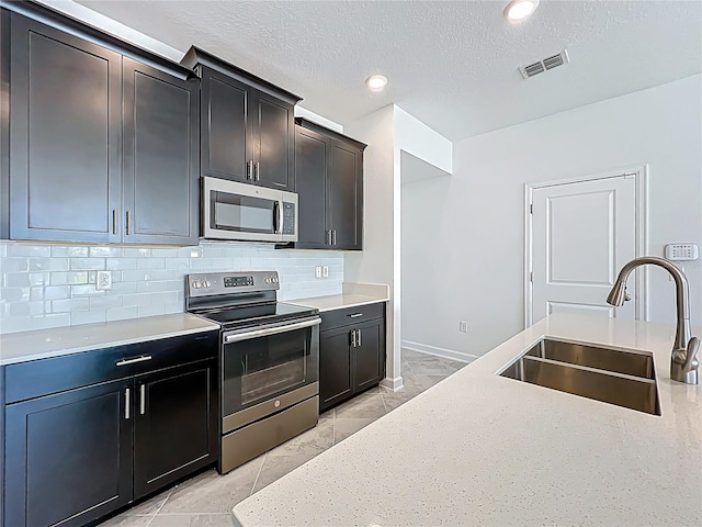 kitchen featuring tasteful backsplash, visible vents, appliances with stainless steel finishes, a textured ceiling, and a sink