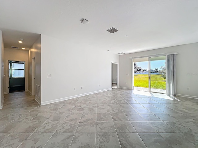 empty room with light tile patterned floors, visible vents, and baseboards