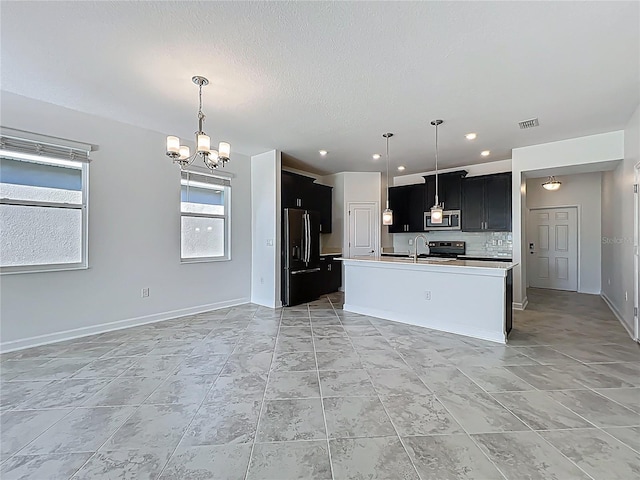 kitchen with stainless steel microwave, visible vents, a chandelier, black fridge, and dark cabinetry