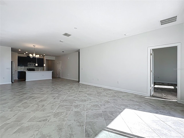 unfurnished living room featuring a notable chandelier, baseboards, and visible vents