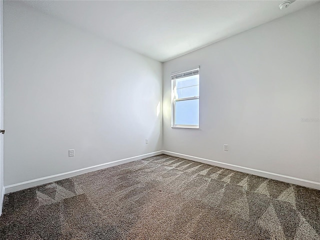 carpeted empty room featuring baseboards