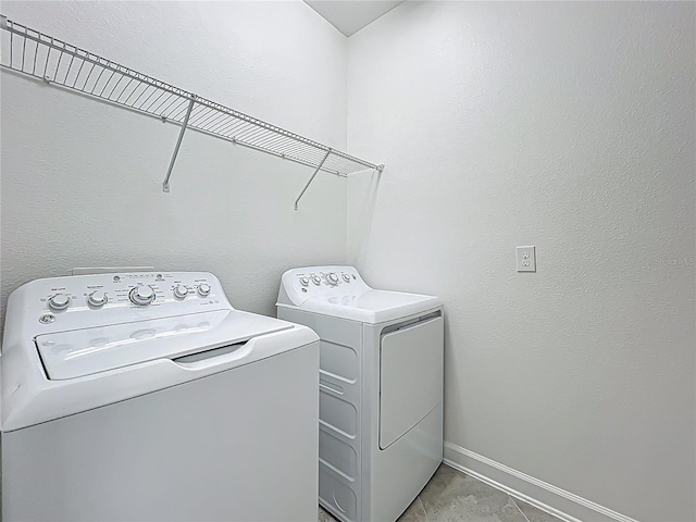 washroom featuring laundry area, baseboards, and washer and clothes dryer