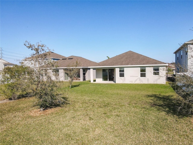 rear view of house with stucco siding and a lawn