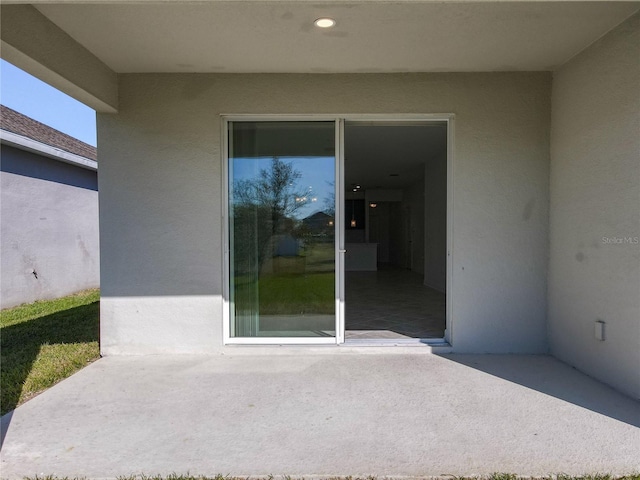 view of exterior entry featuring a patio and stucco siding