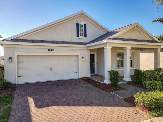 view of front of house featuring stucco siding, decorative driveway, a garage, and a shingled roof