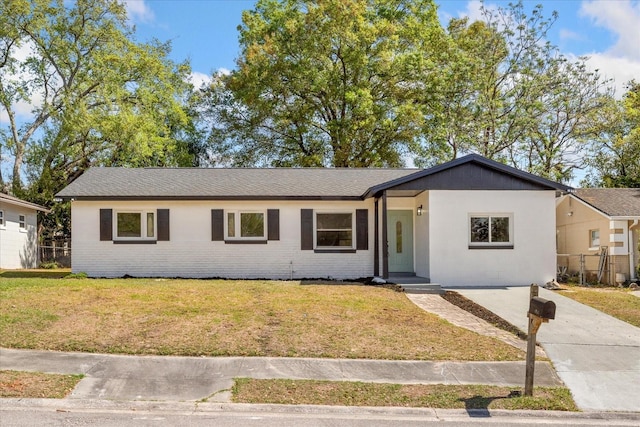 single story home featuring brick siding, concrete driveway, a front yard, and fence