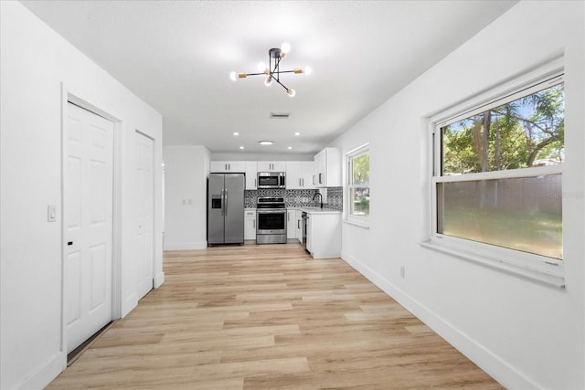 kitchen featuring backsplash, a chandelier, light countertops, appliances with stainless steel finishes, and a sink