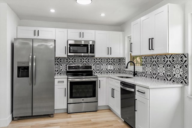 kitchen with white cabinetry, stainless steel appliances, light countertops, and a sink