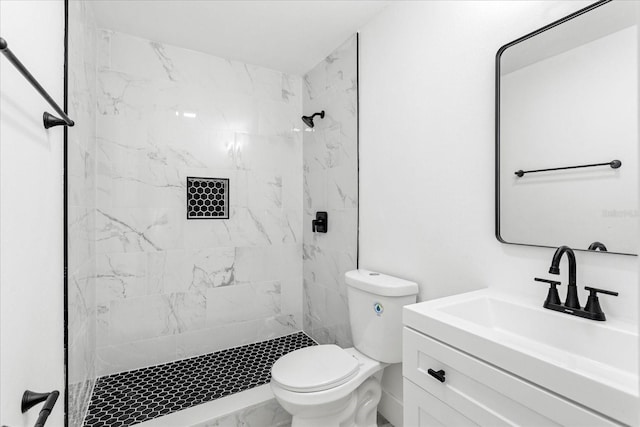 bathroom with marble finish floor, a stall shower, toilet, and vanity