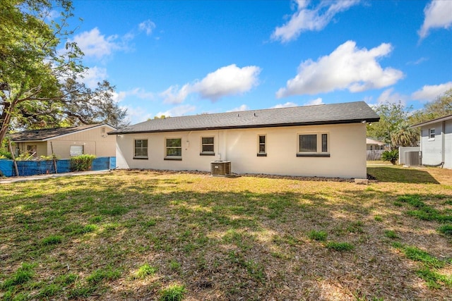 rear view of property with a yard, central air condition unit, and fence