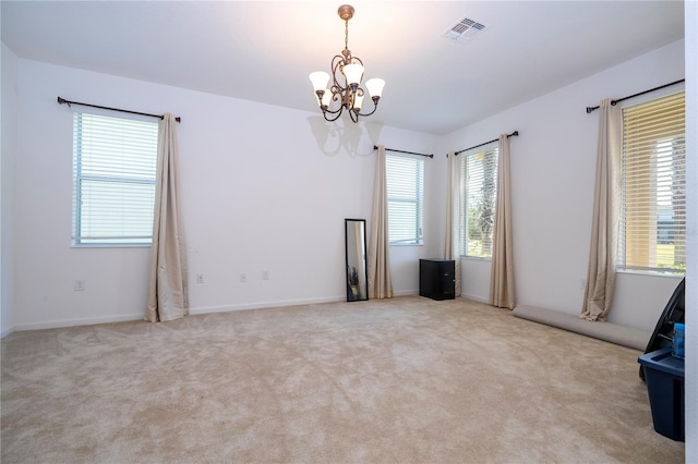 carpeted spare room with a chandelier and visible vents