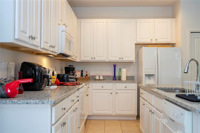 kitchen with white cabinetry, white appliances, light tile patterned flooring, and a sink