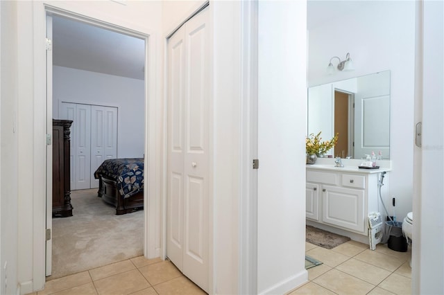 corridor featuring light tile patterned floors and light colored carpet