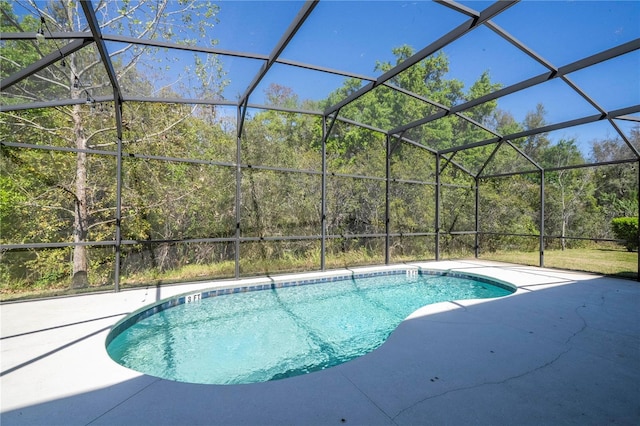 pool featuring a lanai, a view of trees, and a patio