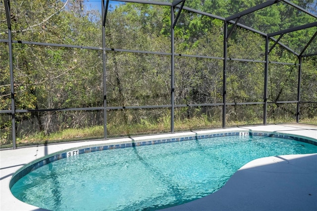 pool with a lanai and a wooded view