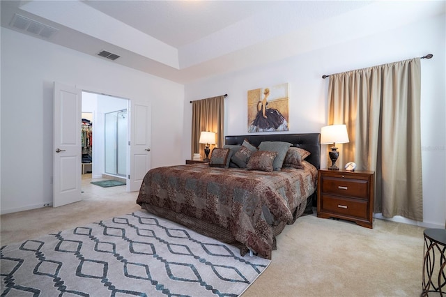 carpeted bedroom with a walk in closet, a tray ceiling, baseboards, and visible vents