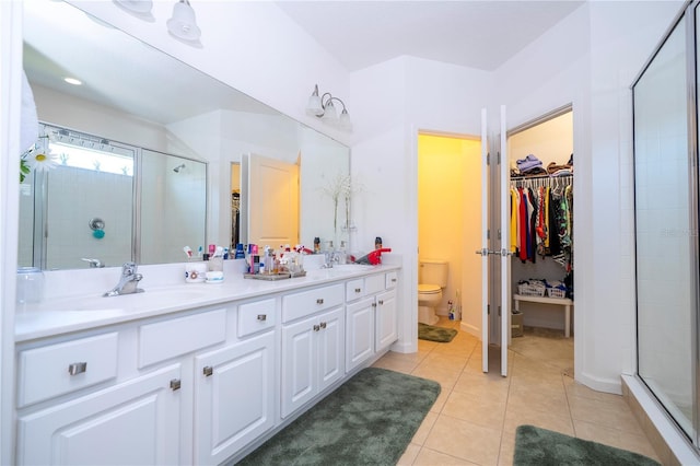 bathroom featuring toilet, a stall shower, a sink, tile patterned flooring, and double vanity