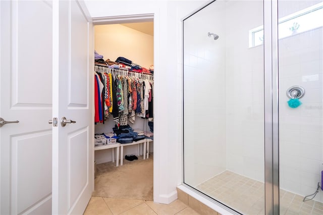 full bath with tile patterned floors, a shower stall, and a spacious closet