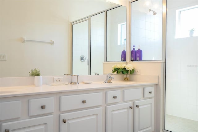 full bath with a sink, a stall shower, and double vanity