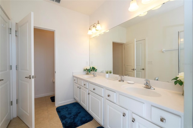 full bathroom with a sink, baseboards, double vanity, and tile patterned floors