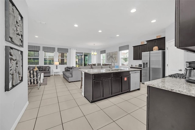 kitchen with light tile patterned flooring, open floor plan, appliances with stainless steel finishes, and a sink