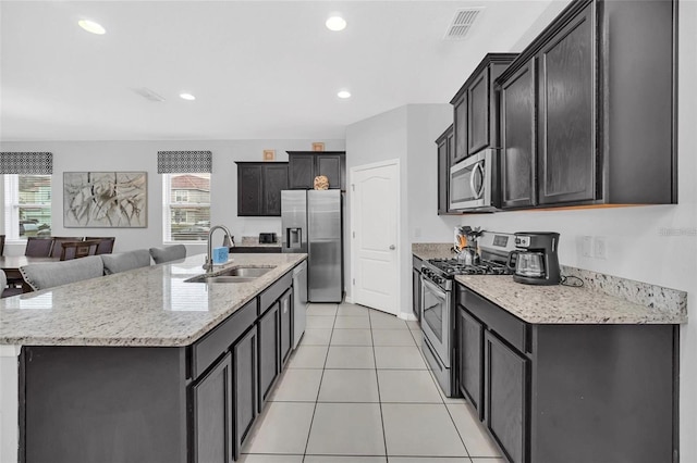 kitchen with light tile patterned floors, visible vents, a center island with sink, a sink, and appliances with stainless steel finishes