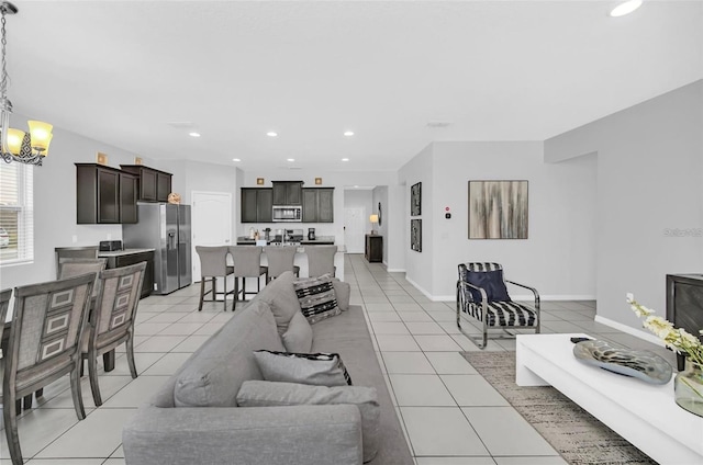 living area featuring light tile patterned floors, a chandelier, recessed lighting, and baseboards