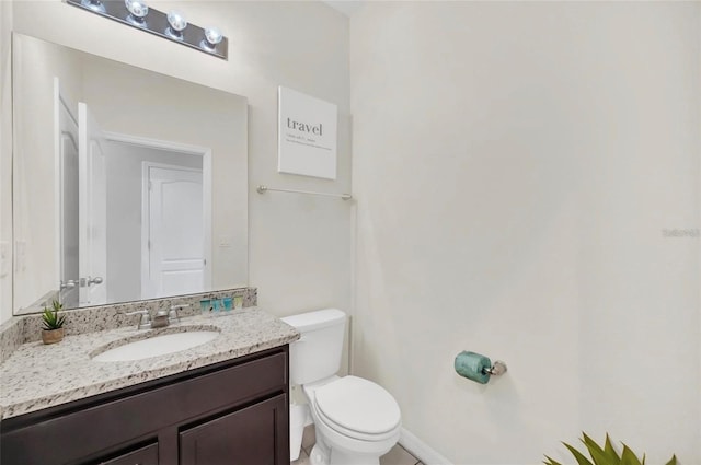 bathroom featuring toilet, vanity, and baseboards