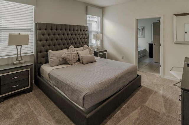 bedroom with light tile patterned floors, baseboards, light carpet, and ensuite bath