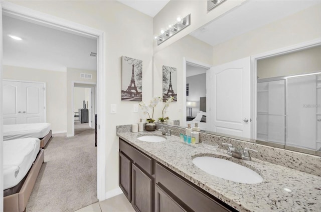 ensuite bathroom featuring double vanity, connected bathroom, visible vents, and a sink