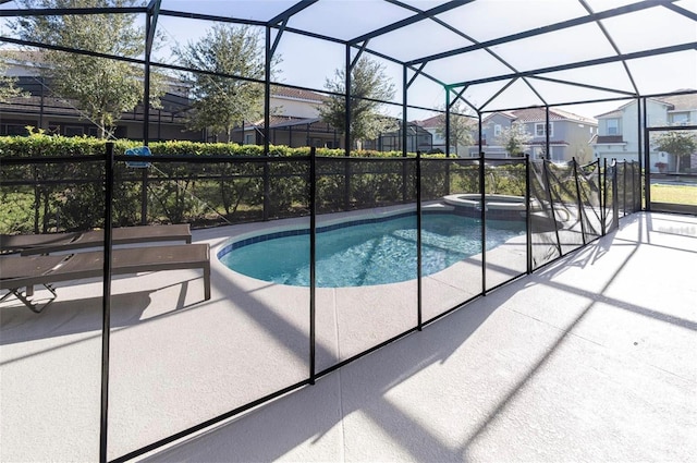 view of swimming pool featuring a residential view, a pool with connected hot tub, a lanai, and a patio area