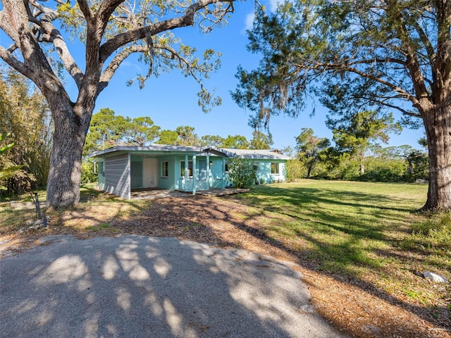 exterior space with driveway, an attached carport, and a front lawn