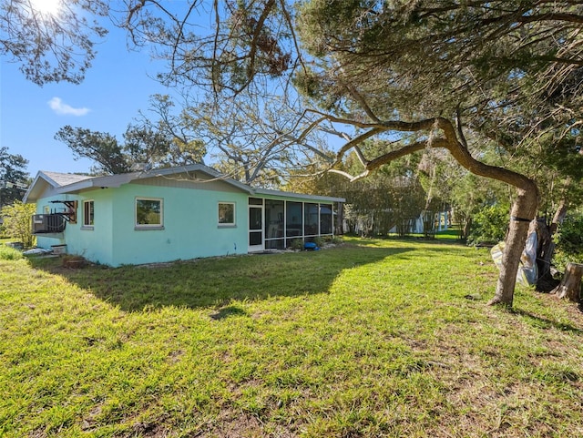 back of house with stucco siding, a yard, and a sunroom