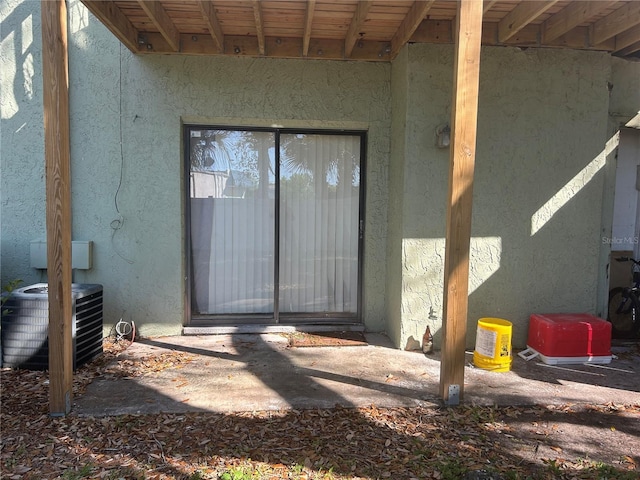 doorway to property featuring stucco siding and central AC unit