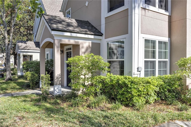 property entrance with stucco siding and roof with shingles