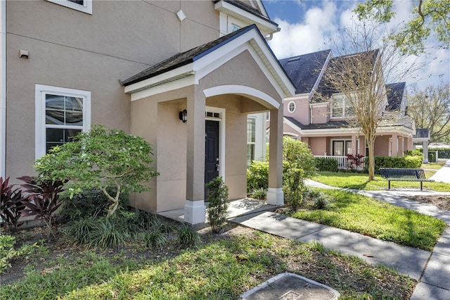 view of exterior entry with fence and stucco siding