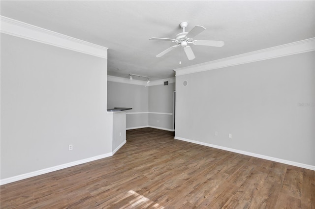 spare room featuring a ceiling fan, crown molding, wood finished floors, and baseboards