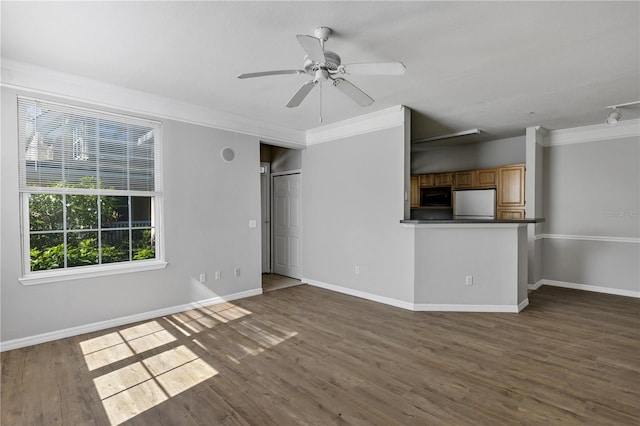 unfurnished living room featuring ceiling fan, baseboards, wood finished floors, and ornamental molding