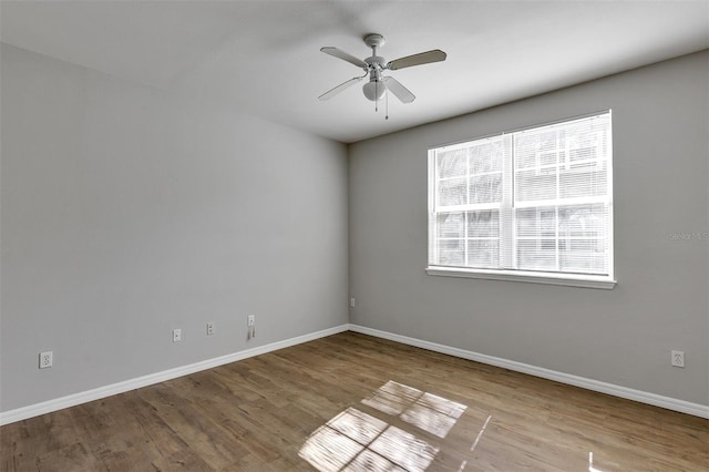 empty room featuring wood finished floors, baseboards, and ceiling fan