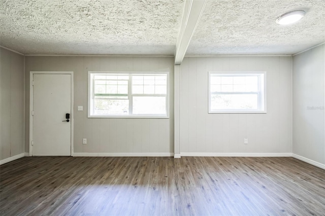 unfurnished room with ornamental molding, a textured ceiling, baseboards, and wood finished floors