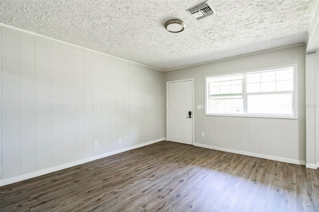 unfurnished room featuring a textured ceiling, wood finished floors, visible vents, and baseboards